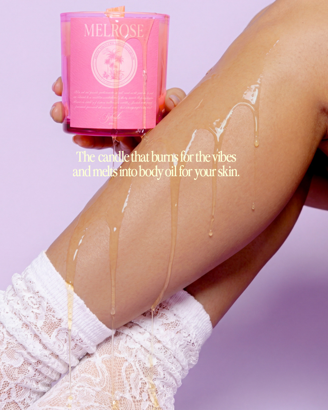 Pink candle labeled 'Melrose' being held near a person's leg with wax body oil dripping from the candle wax.